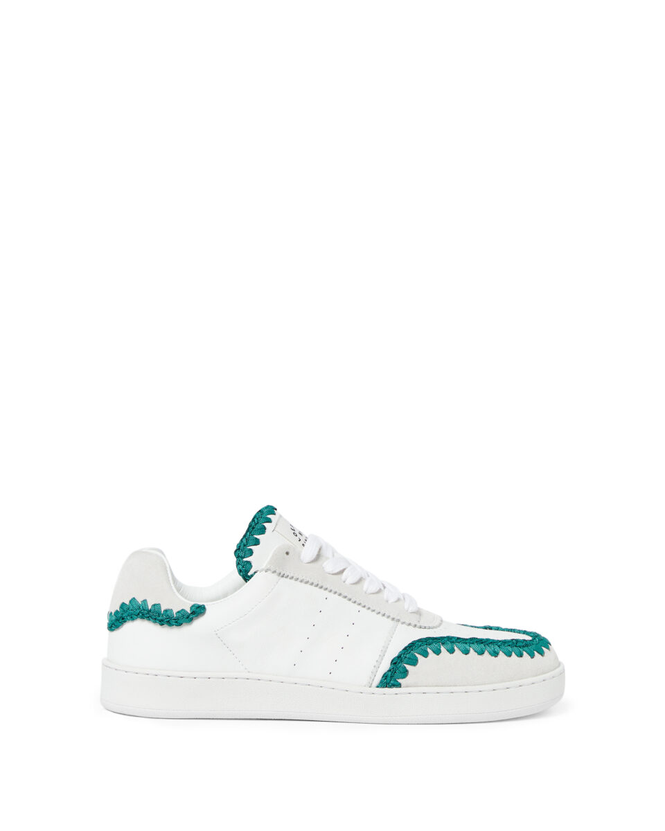 White leather low-top sneaker with suede panels and teal whipstitch trim on a white background, for Loeffler Randall.